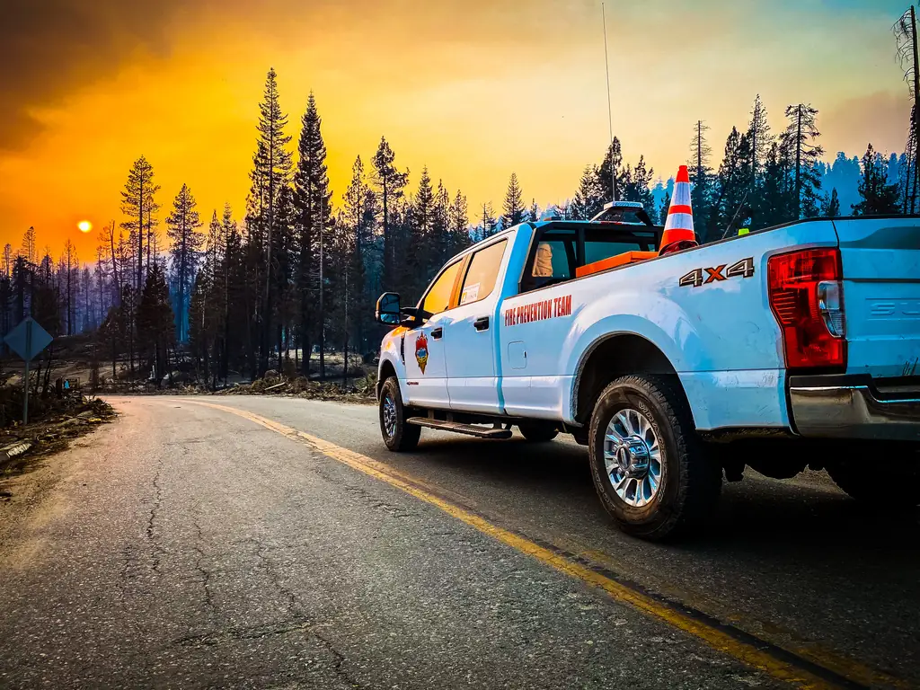 Fire prevention team pickup on a forest road beneath an orange sky